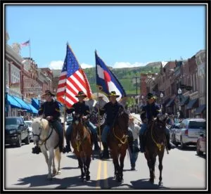 3 men riding on horseback holding flags